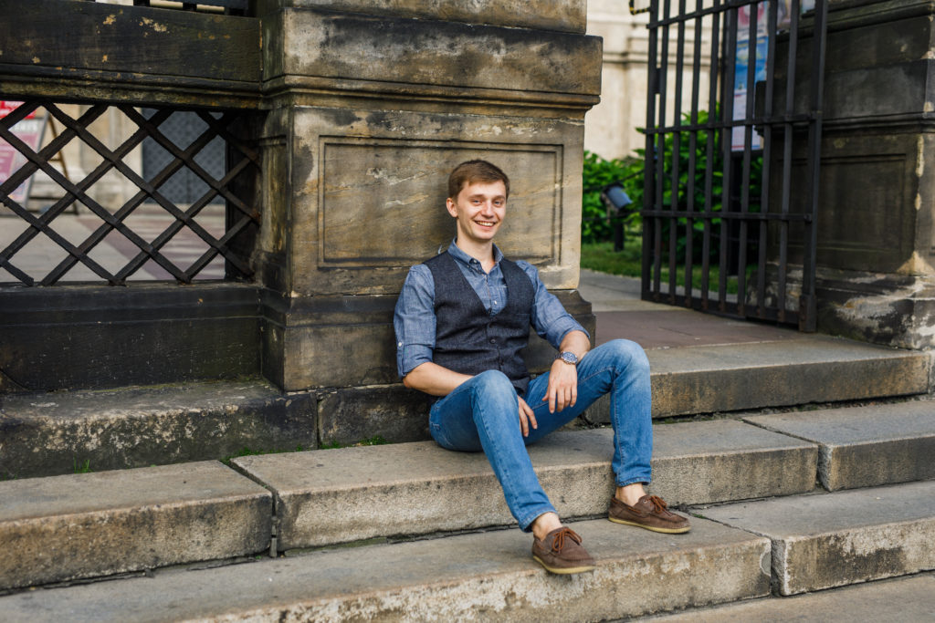 portrait of a man in a blue shirt and blue pants sitting on the steps
