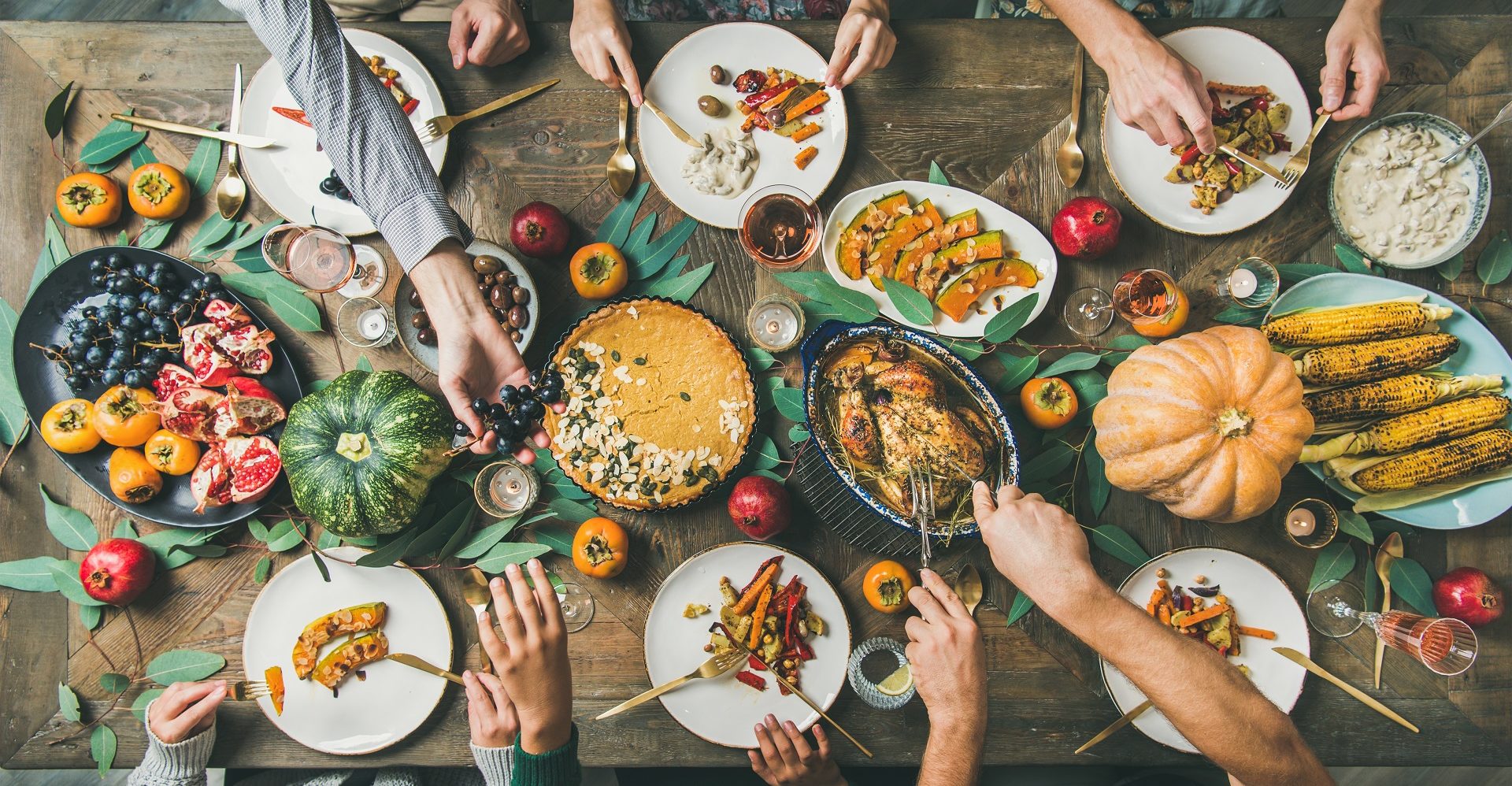 Friends feasting at Thanksgiving Day table with turkey, top view