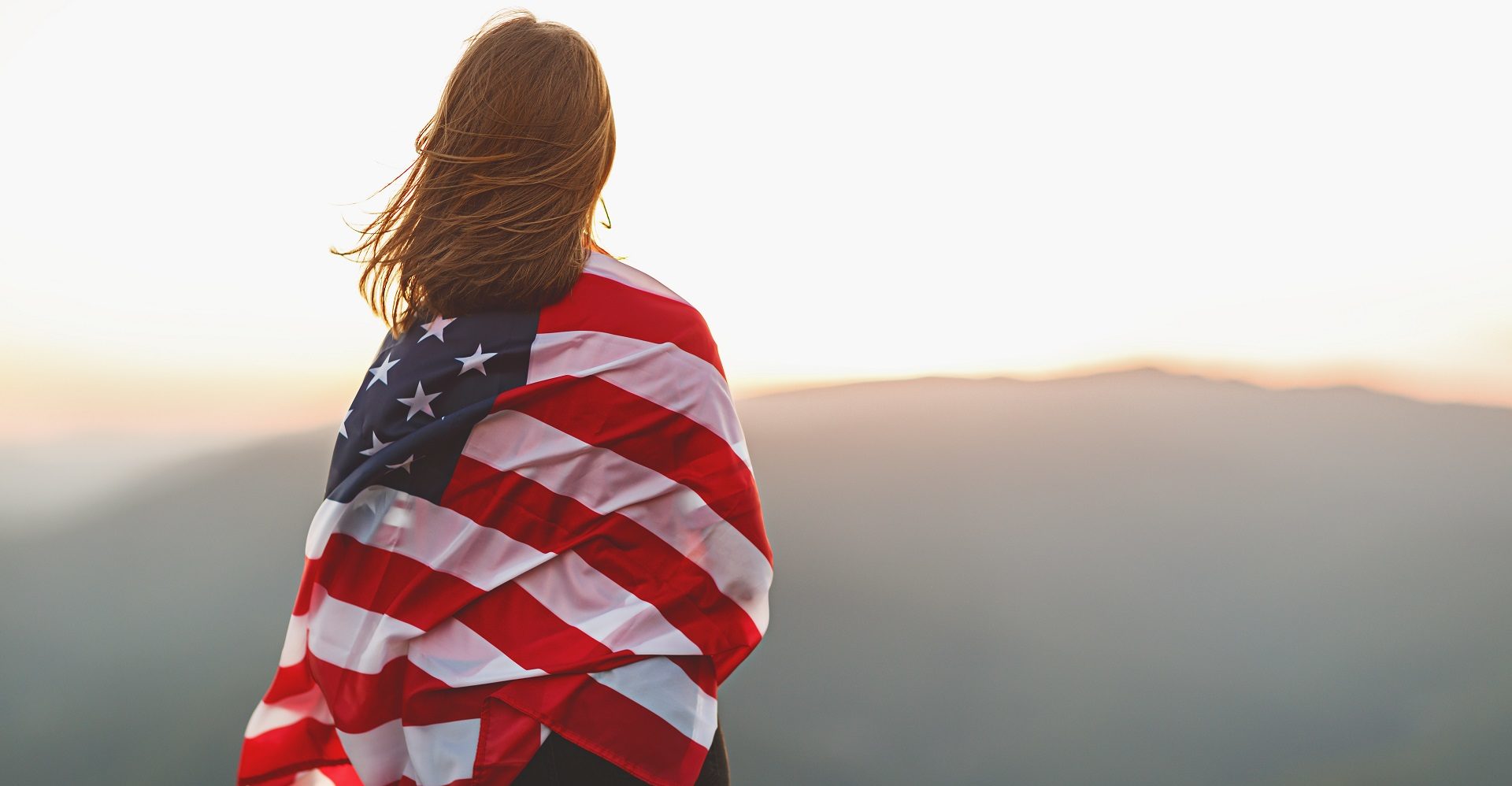 happy woman with flag of united states enjoying the sunset on nature
