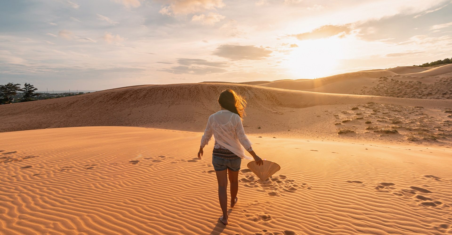 Young woman traveler looking sunset at red sand dunes in Vietnam, Travel lifestyle concept