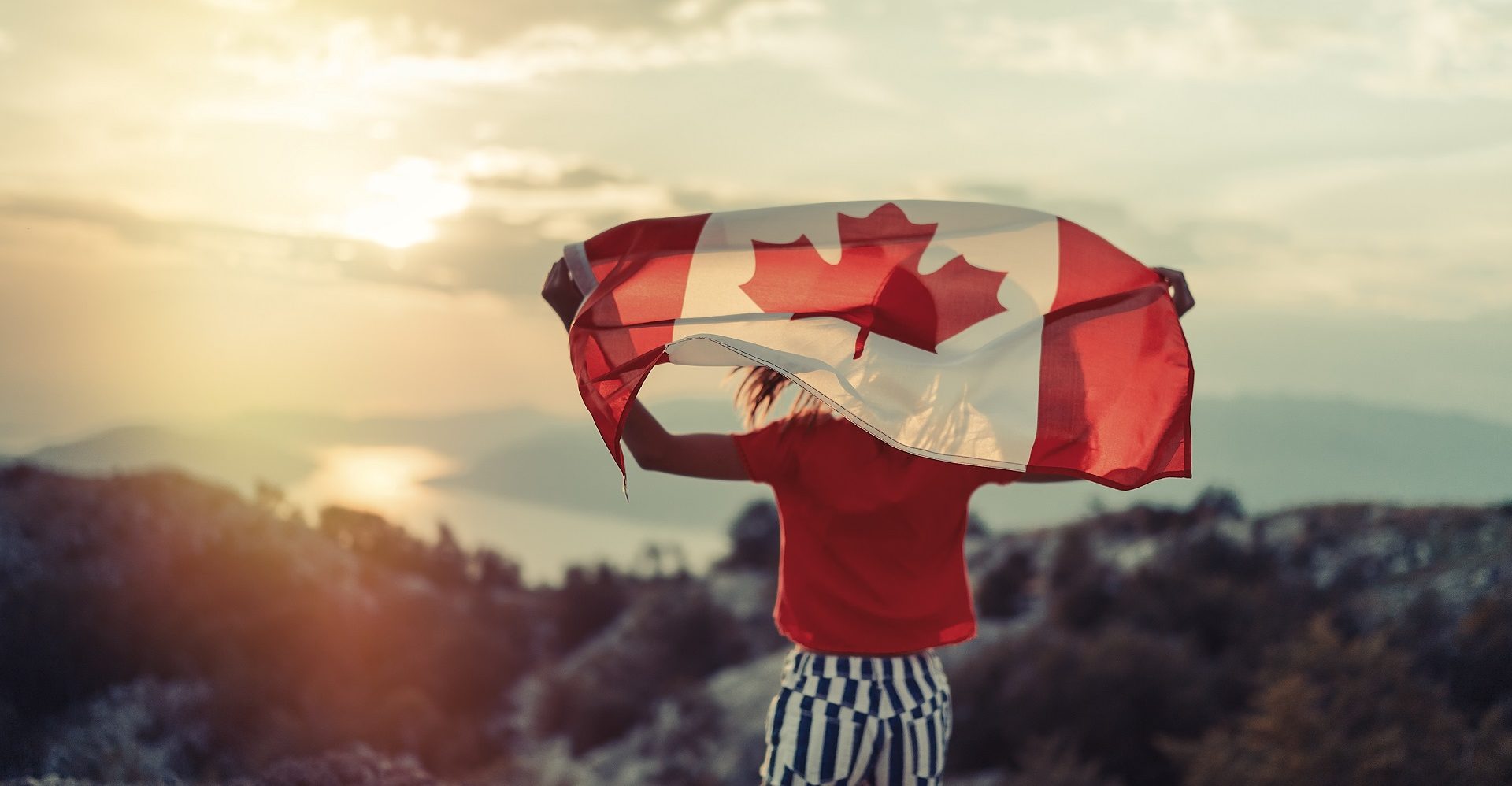 Happy child teenage girl waving the flag of Canada while running